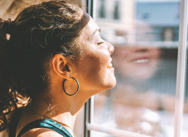 Woman near window with sun on face