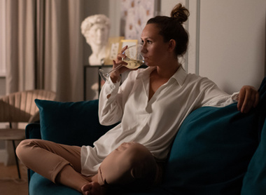 Woman drinking glass of wine on sofa